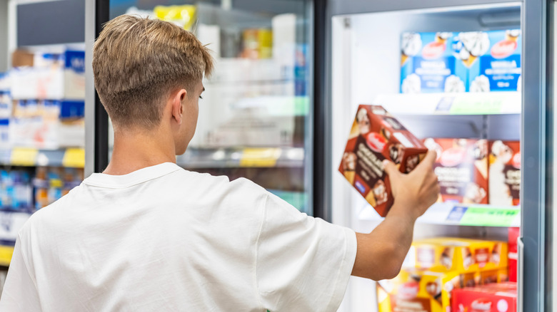 Man choosing box of frozen food from a supermarket freezer
