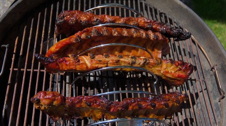 Four ribs arranged on a rib rack over the grill