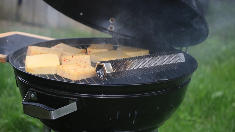 a smoke tube inside a grill next to cheese