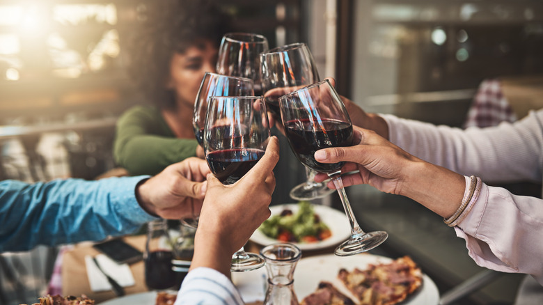 A gathering of friends at a dinner party, cheersing wine glasses.