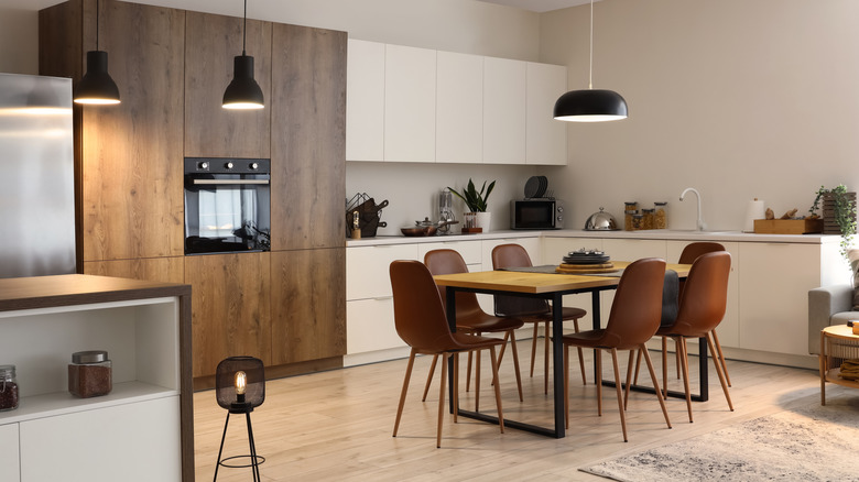 Modern kitchen and dining room with kitchen table under main lighting fixture.