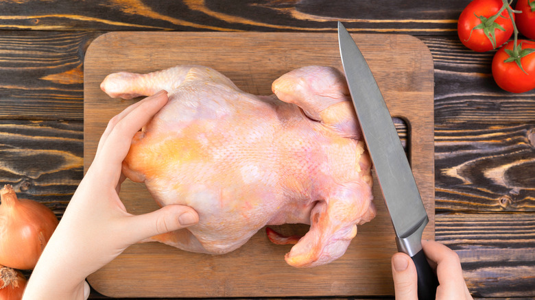 Person getting ready to debone a chicken on a cutting board