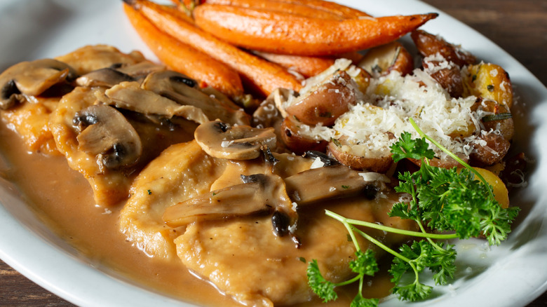 Plate of chicken Marsala with carrots and parsley on side