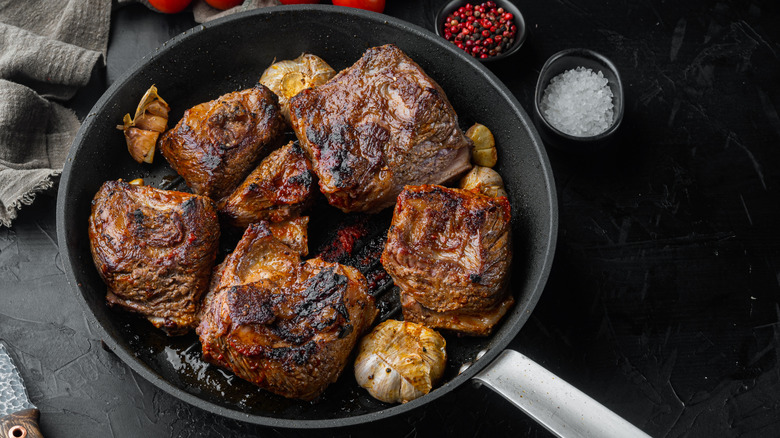 Browned short ribs on a skillet with various seasonings