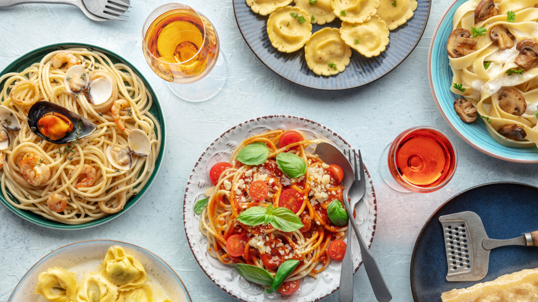 Top-down photo of various plates of pasta and glasses of wine on a table