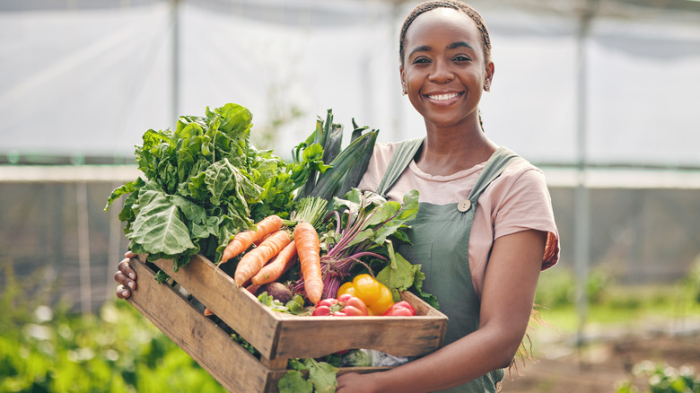A farmer holding a box of vegetables.
