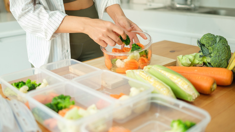Woman pre-cuts and sorts produce into containers in kitchen