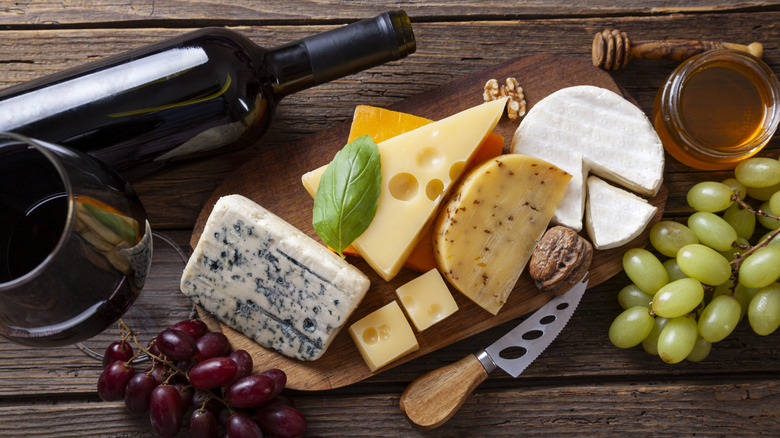 Cheese, grapes, nuts, honey, and red wine on a wooden background