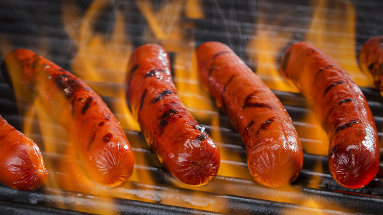 Several hot dogs being grilled over an open flame