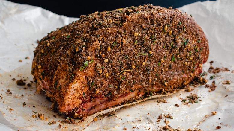 A piece of raw beef covered in a dry rub