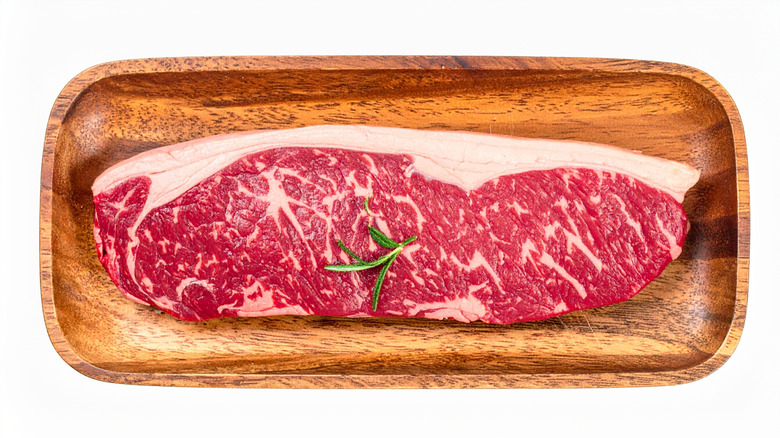 New York strip steak with rosemary on a wooded plate