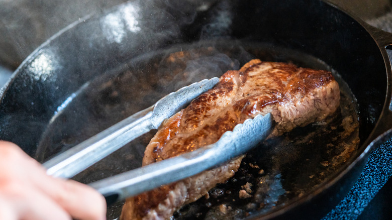 Searing a New York strip steak in a cast iron skillet