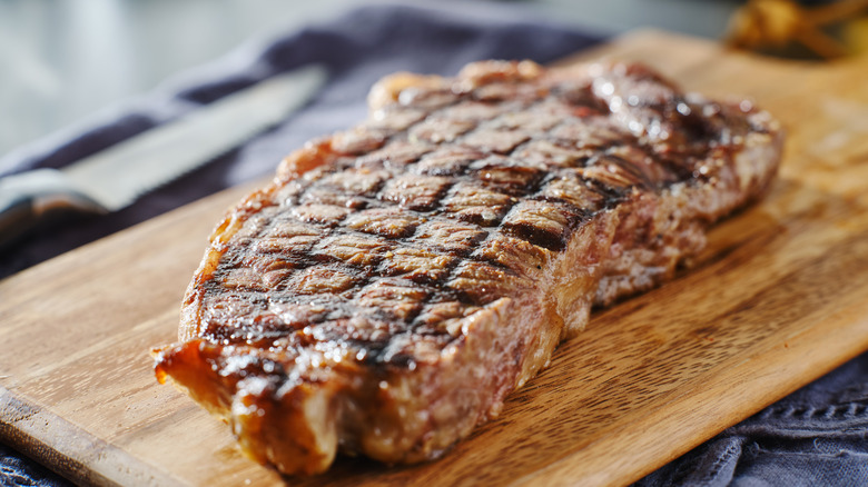 A New York strip steak resting on a cutting board