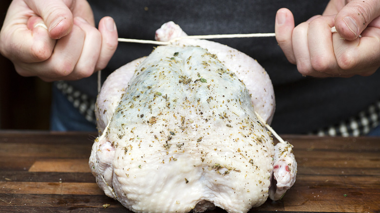 Person trussing whole chicken