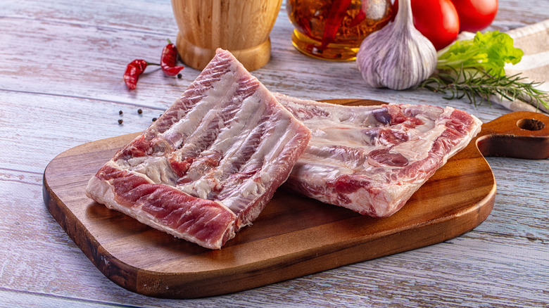 Uncooked baby back ribs on a cutting board.