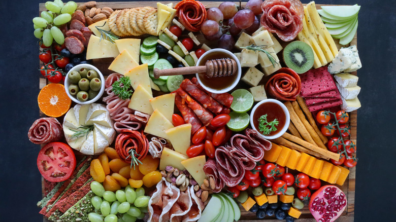 Charcuterie board with olives, vegetables, cheeses, meats, and dips