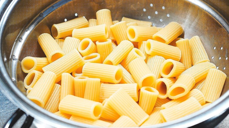 Cooked rigatoni in a stainless steel colander