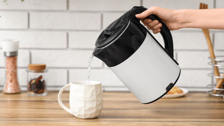 Someone pouring water from an electric kettle