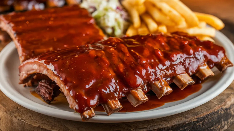 Baby back ribs are cloaked in a bright, red sauce.