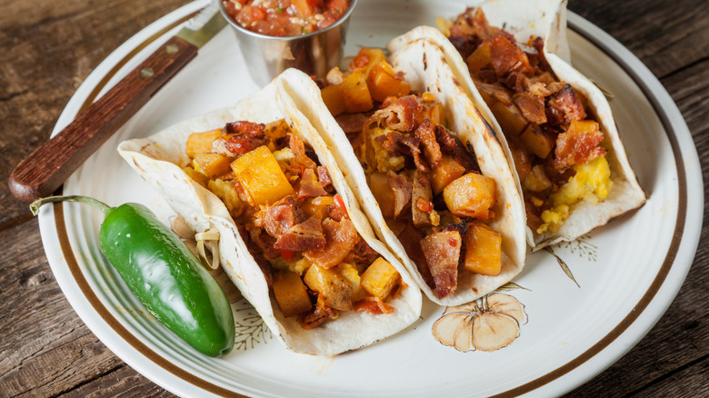 Plate of three breakfast tacos with a whole jalapeno on plate.