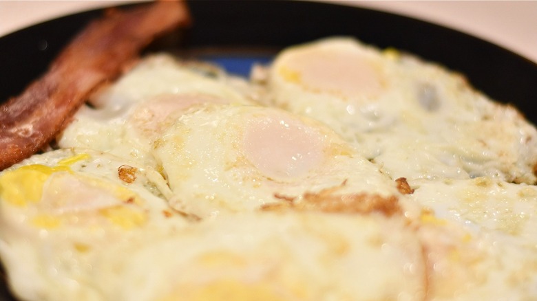 A plate of fried eggs with a bacon strip