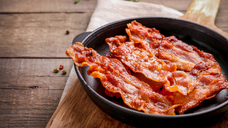 A dish of crisp bacon sits on a cutting board.