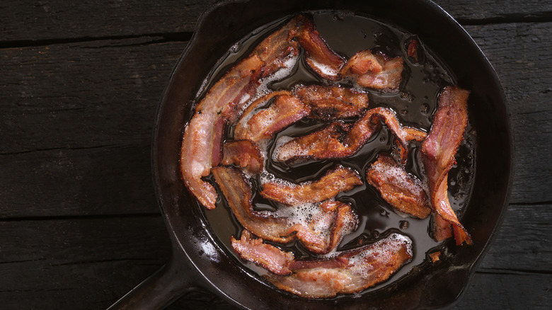 Bacon frying in a cast iron pan.