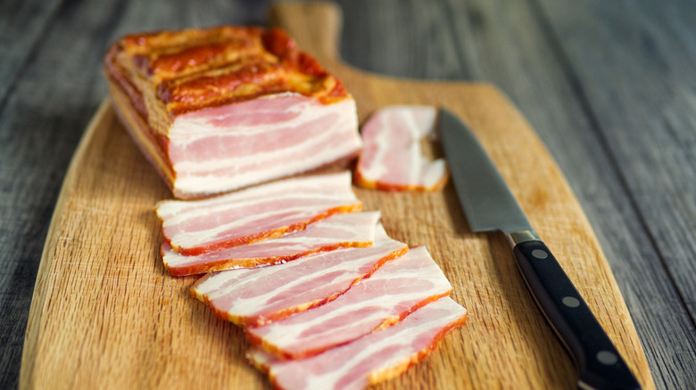 A slab of bacon on a cutting board.