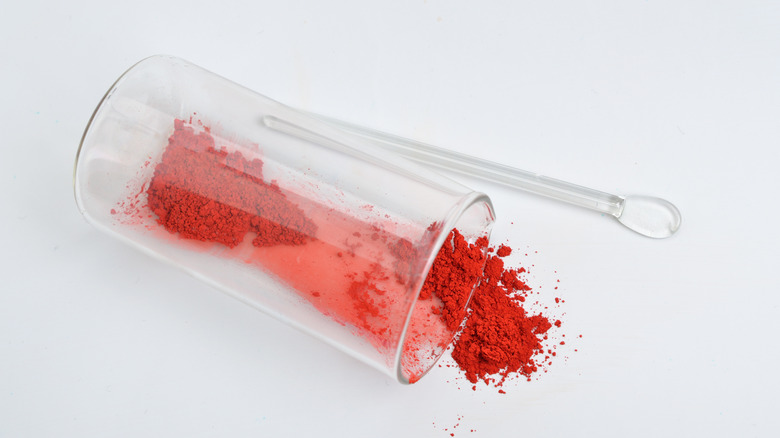 Carmine dye spills from clear glass beaker