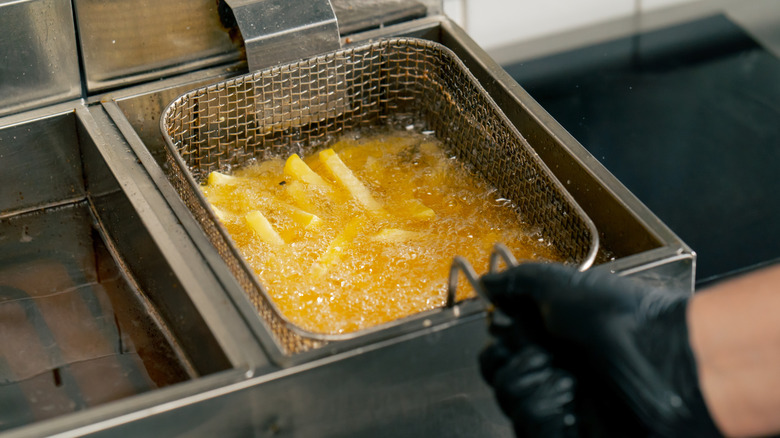 person dipping french fries into oil