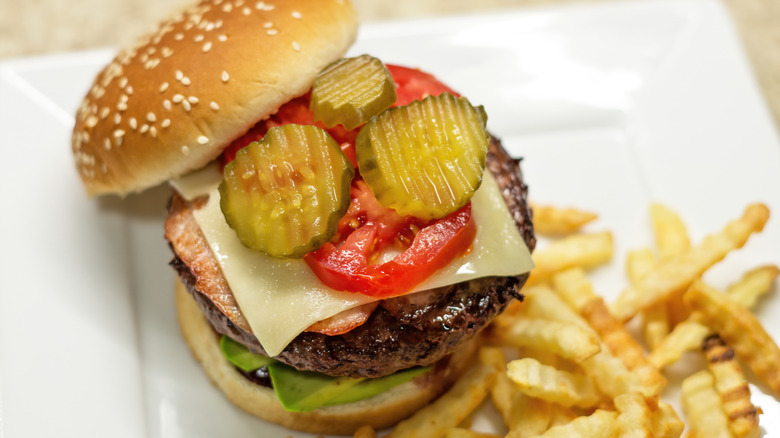 Open-face burger with pickles on top layer