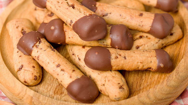 Close-up of chocolate-dipped chocolate chip shortbread cookie sticks on a circular wooden plate