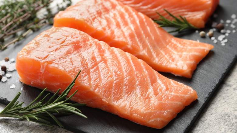 Uncooked salmon filets on a stone board.