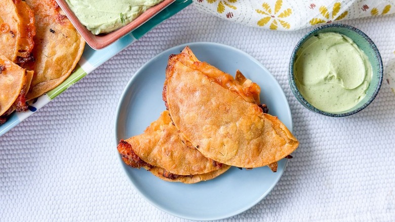 Baked crispy beef tacos on serving plate with avocado crema