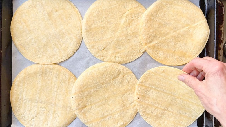 Flipping corn tortillas on parchment-lined sheet pan