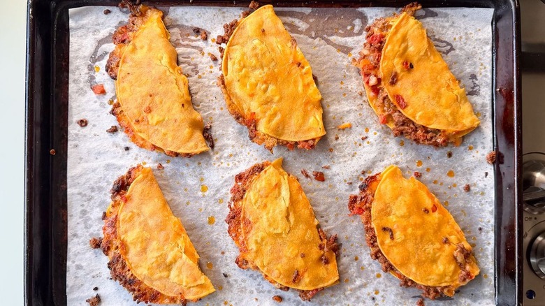 Baked crispy beef tacos on parchment-lined sheet pan