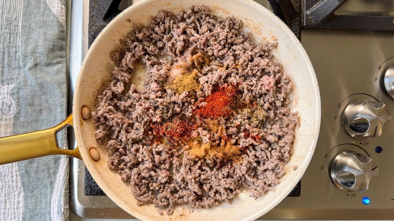 Browned ground beef and spices in skillet on stovetop