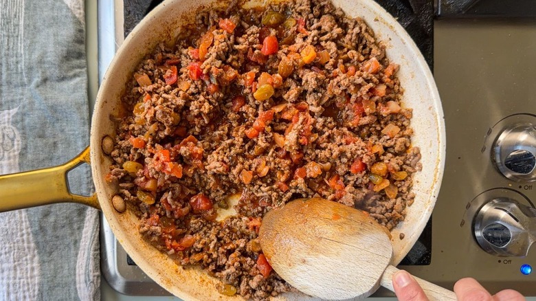 Browned ground beef, salsa, and golden raisins in skillet on stovetop