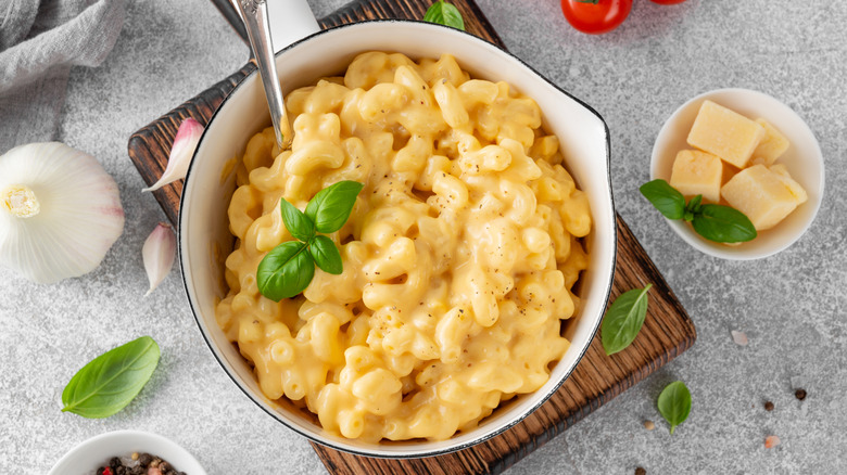 Macaroni and cheese in a ceramic bowl on a cutting board.