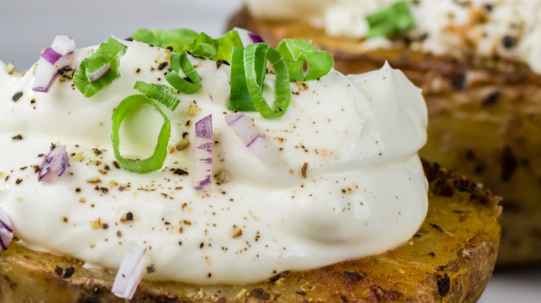 A baked potato topped with french onion dip and onions