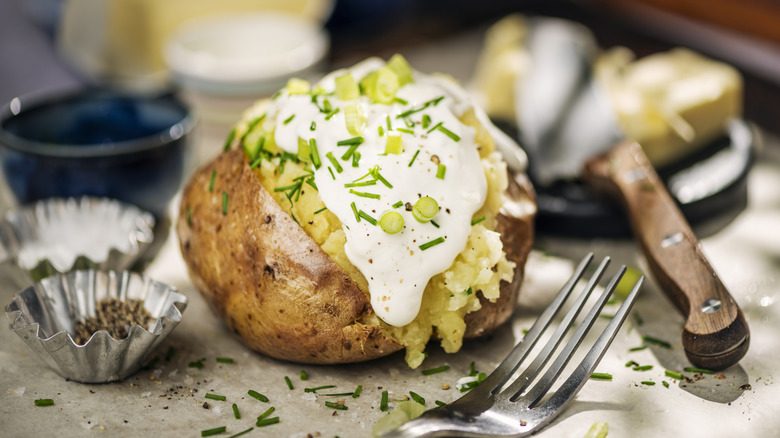 A baked potato topped with sour cream and chives