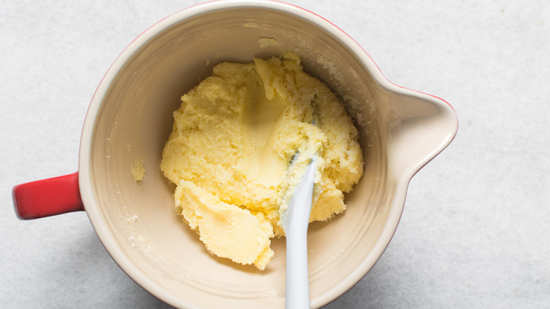 Creamed butter and sugar in a crock container with a spatula