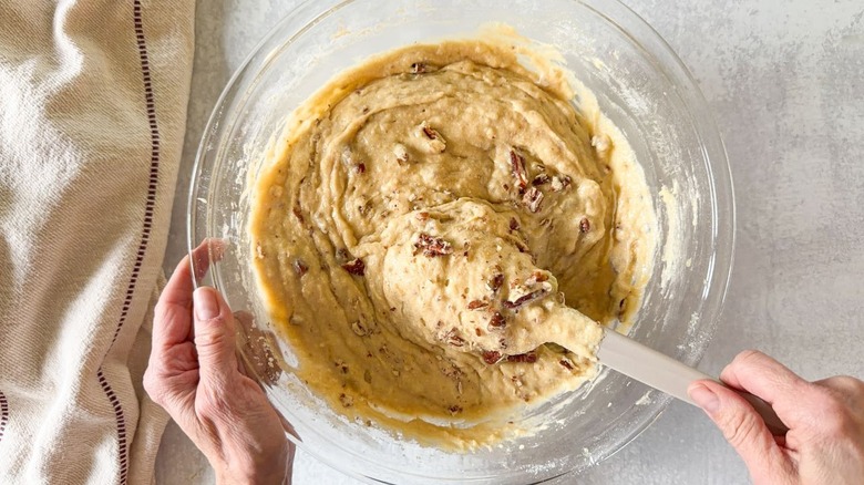 Stirring chopped pecans into bakery-worthy banana bread batter