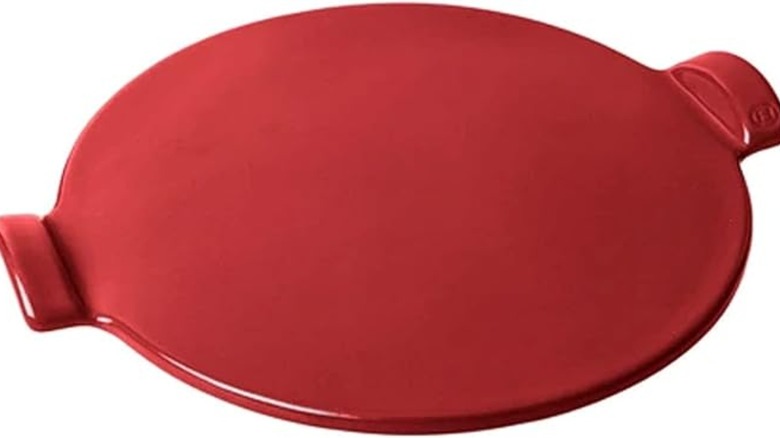 Emile Henry red pizza stone on a white surface