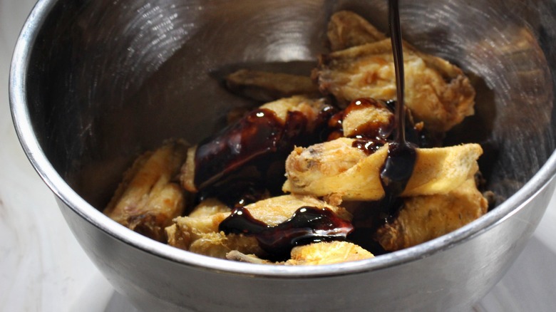 pouring glazed on fried chicken wings