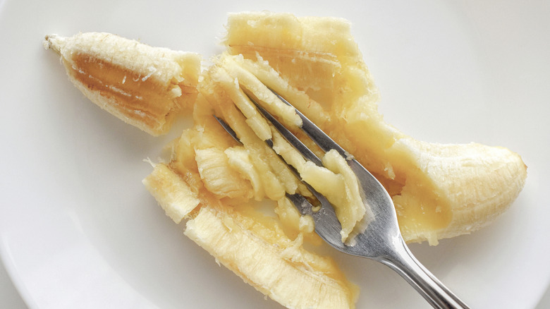 Ripe banana being mashed with a fork