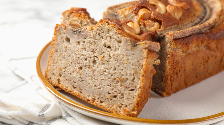 Cut banana bread with nuts on table, closeup
