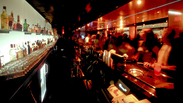 A busy bar with customers looking to get the attention of their bartender