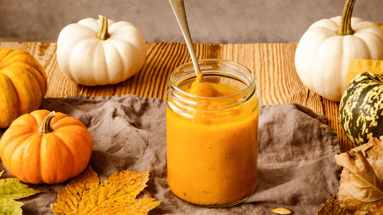 pumpkin puree in a jar surrounded by seasonal decor