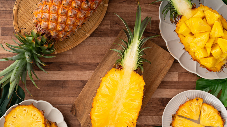 A pineapple, cut in half, on a wooden table.